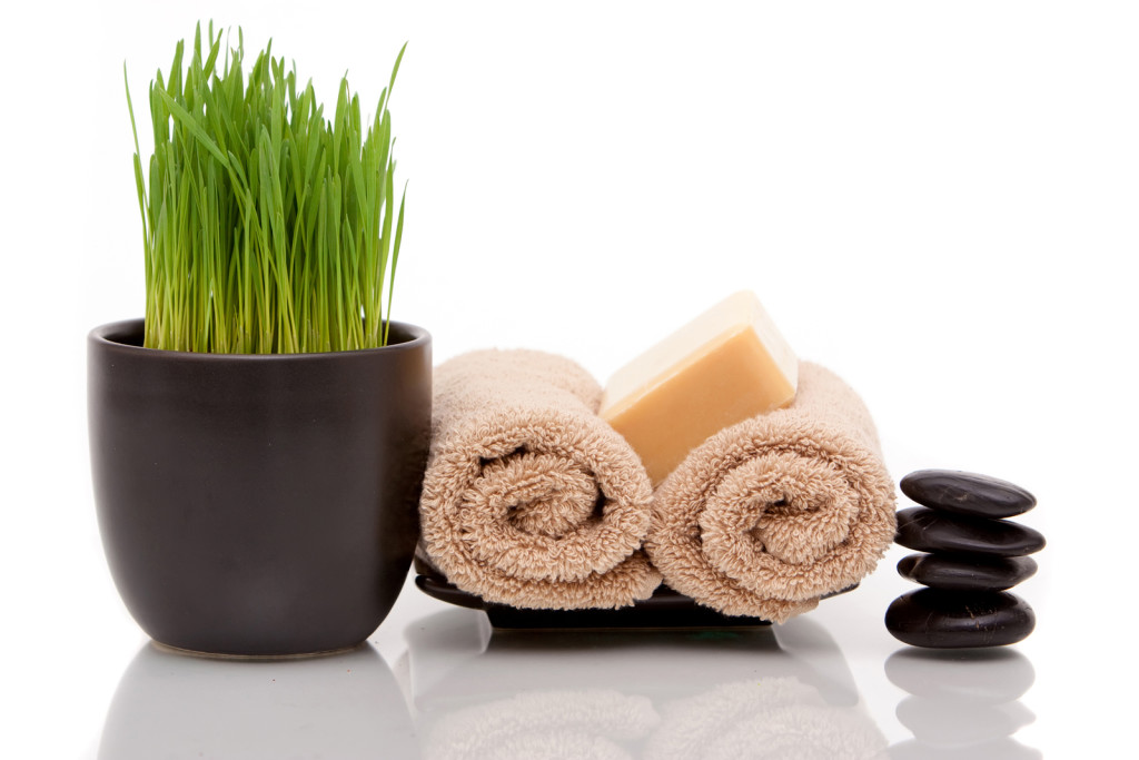 Spa towel, soap and wheatgrass on white background